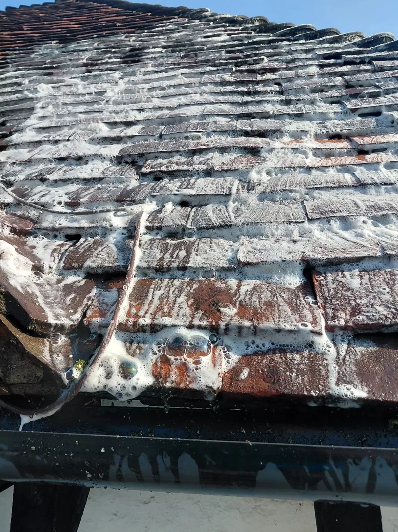 Close-up of cleaning treatment foaming on clay roof tiles